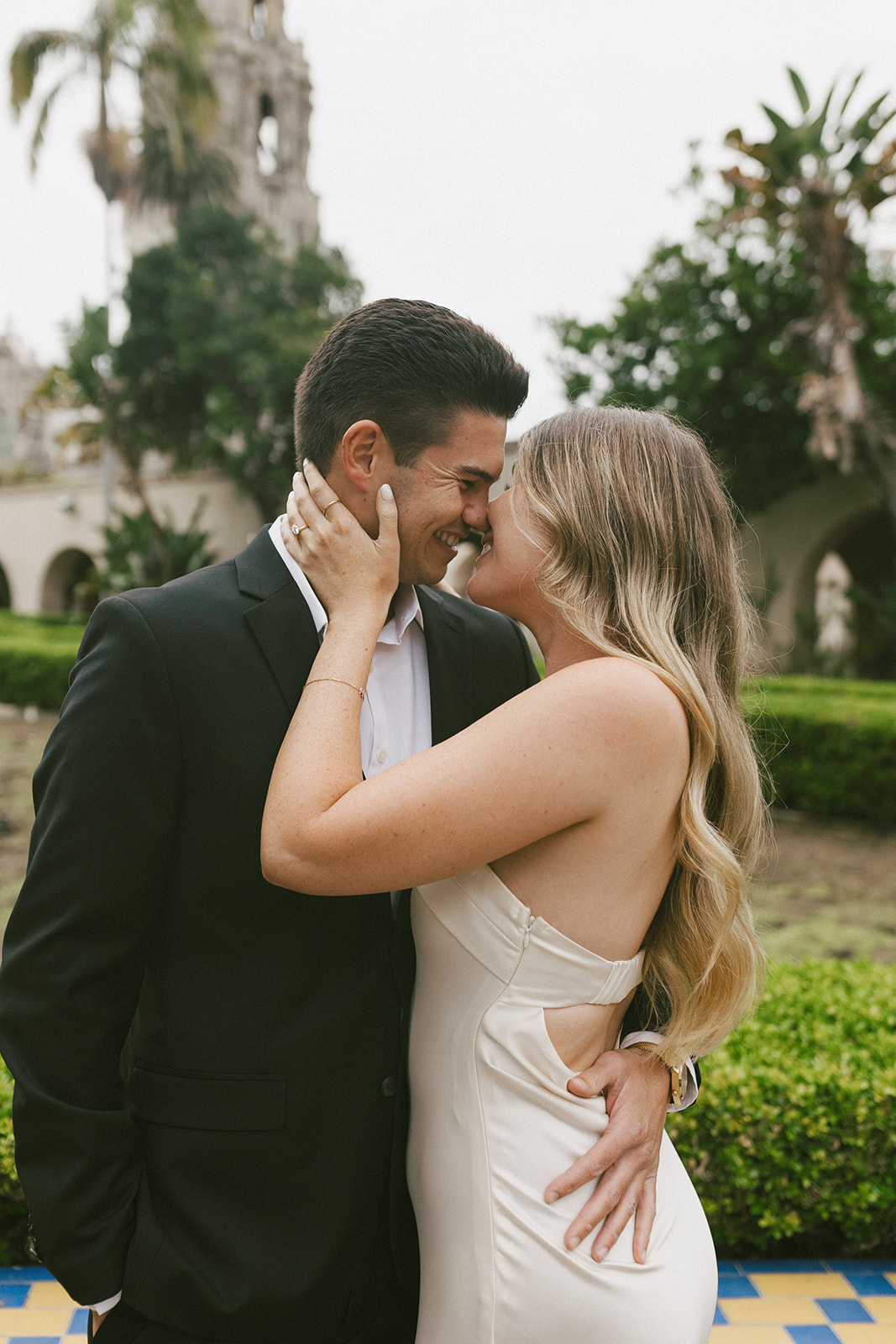 Romantic Balboa Park engagement photo with couple embracing near California Tower