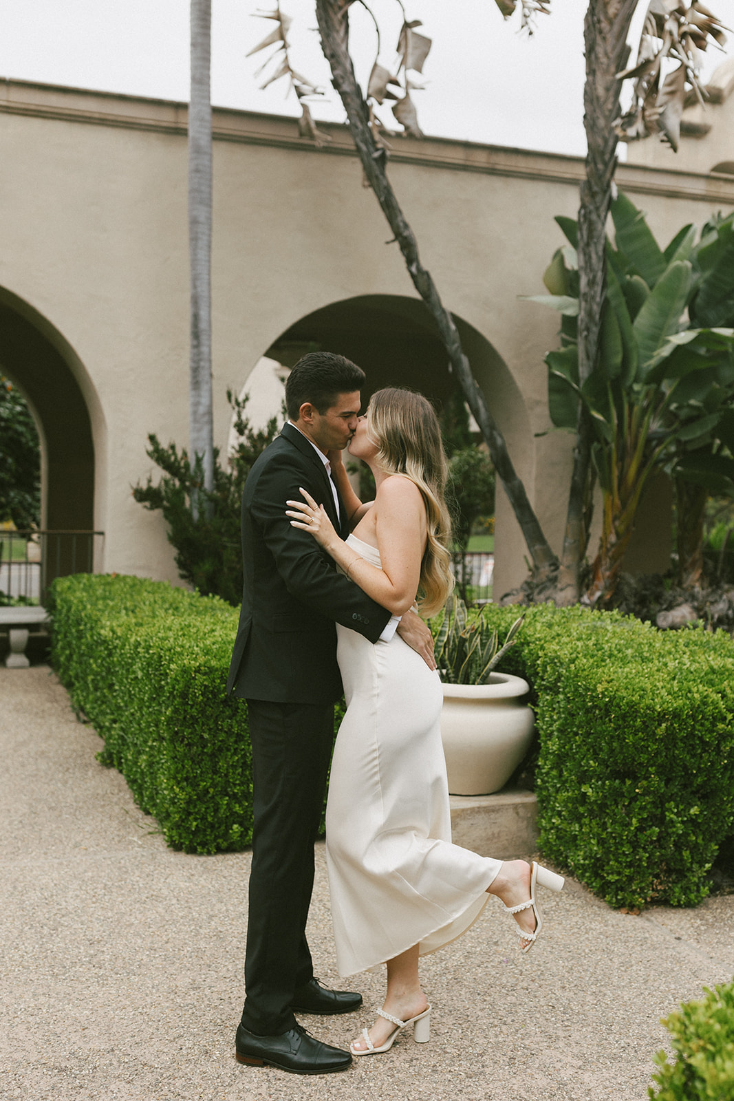 Couple kissing in lush courtyard during Balboa Park engagement session