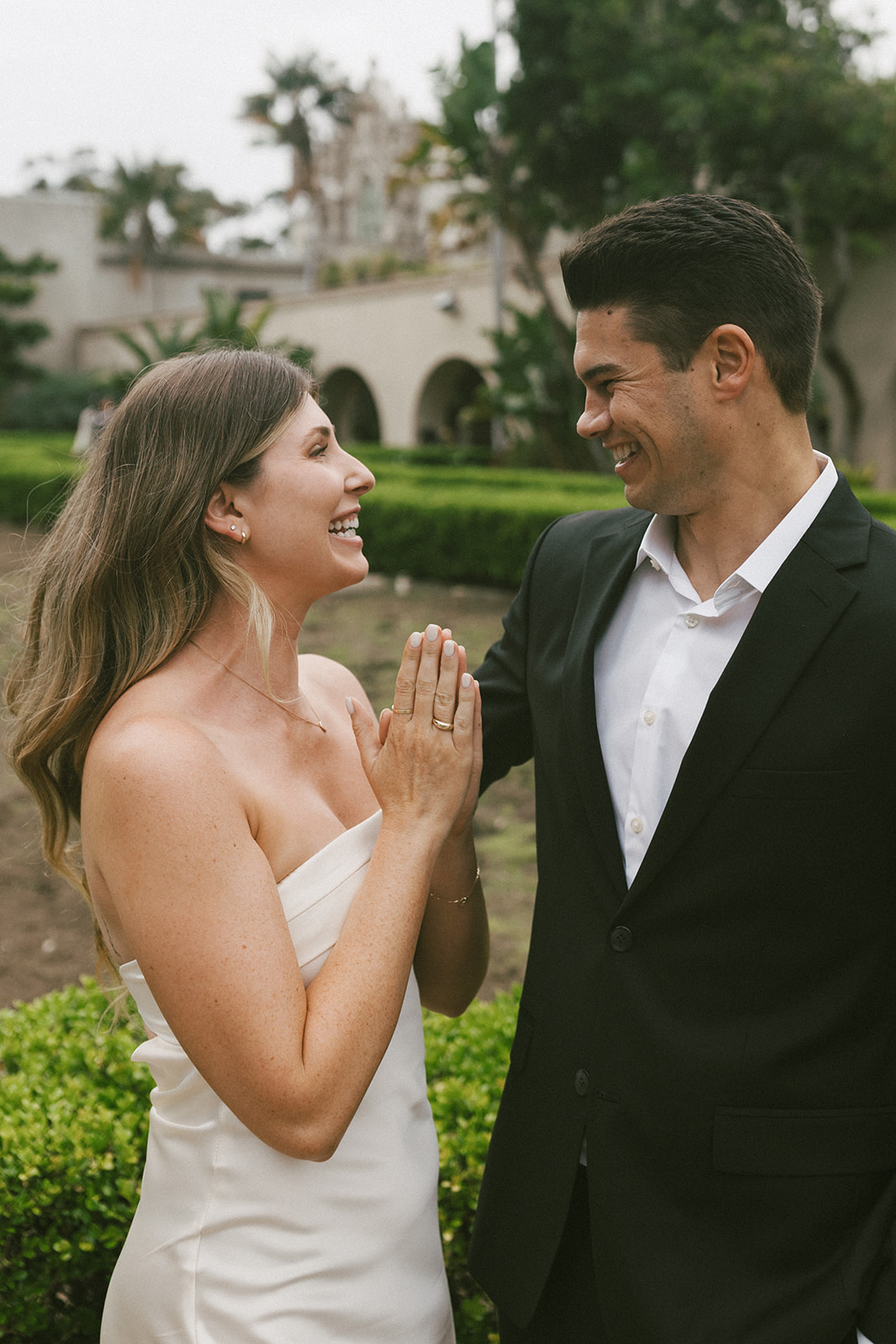 Joyful couple during Balboa Park engagement session near arched walkway