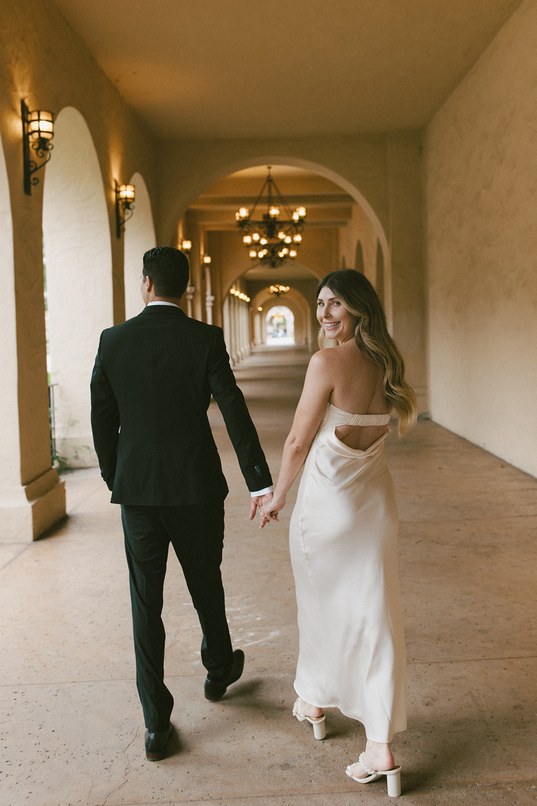 Romantic Balboa Park engagement photo under arched Spanish-style corridor