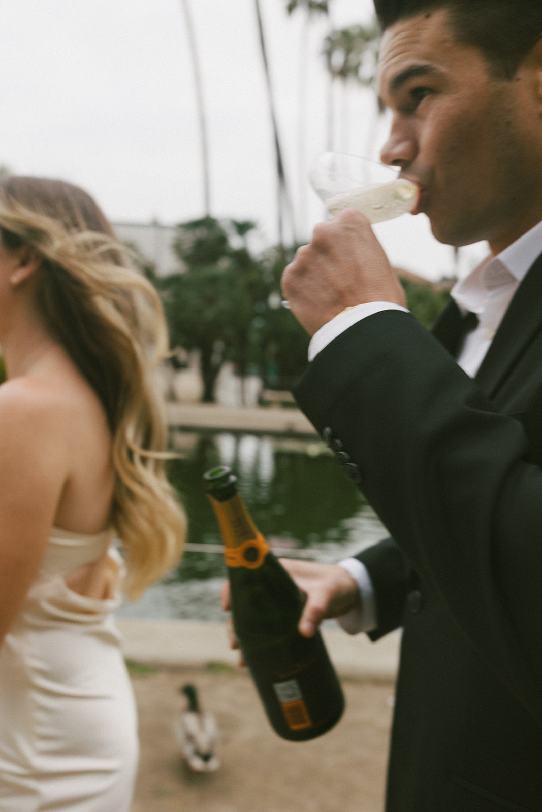 Playful Balboa Park engagement photo with champagne toast by reflecting pond
