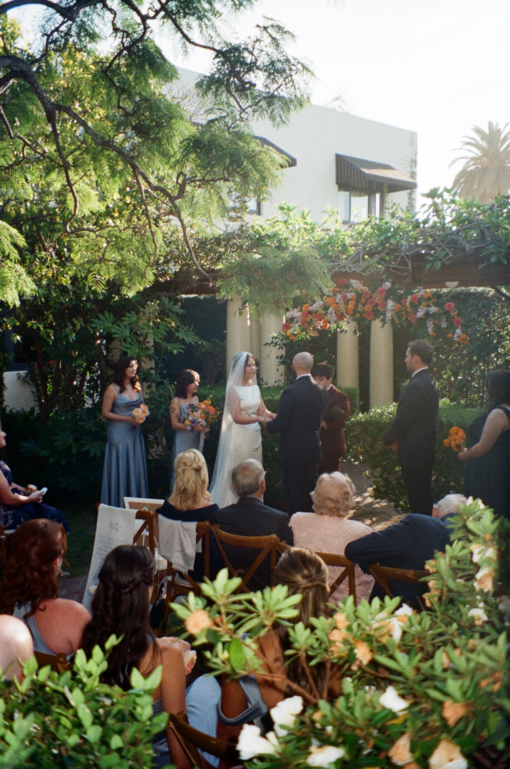 Bride and groom exchanging vows under floral arbor at San Diego garden venue