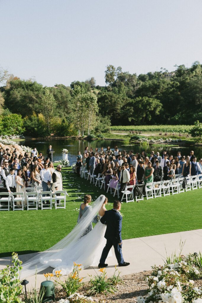 Lakeside wedding ceremony with white chairs at San Diego vineyard venue
