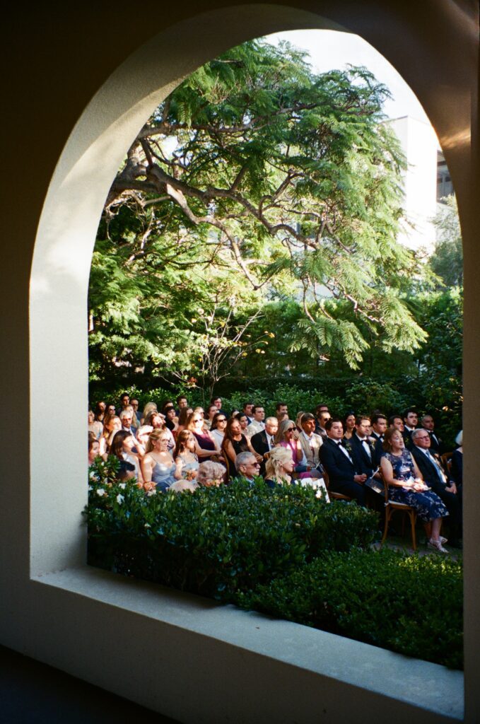 Guests seated in lush courtyard for outdoor wedding ceremony in San Diego